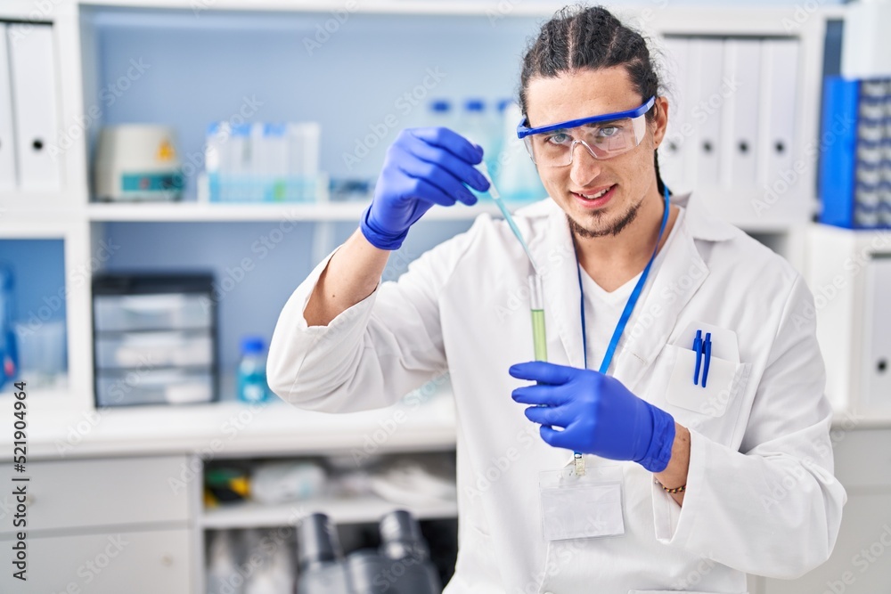 Young man wearing scientist uniform measuring liquid at laboratory