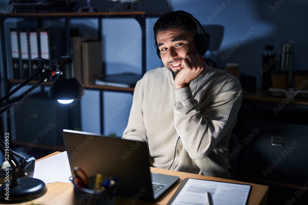 Young handsome man working using computer laptop at night looking stressed and nervous with hands on mouth biting nails. anxiety problem.