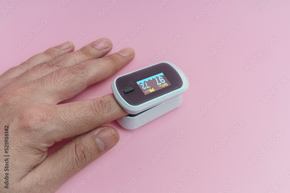 Mano, medición con oximetro y pulsometro sobre fondo rosa. Mano, medición con oximetro y pulsometro sobre fondo rosa.