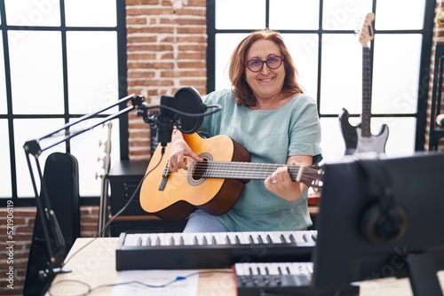 Senior woman musician smiling confident playing classical guitar at music studio