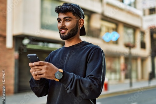 Young arab man smiling confident using smartphone at street