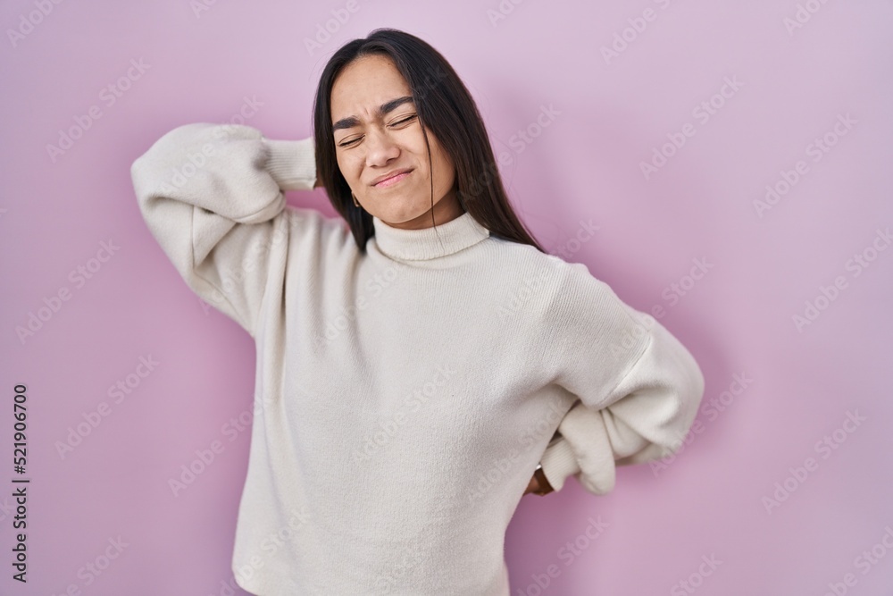 Young south asian woman standing over pink background suffering of neck ache injury, touching neck with hand, muscular pain Young south asian woman standing over pink background suffering of neck ache injury, touching neck with hand, muscular pain