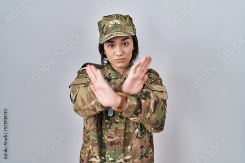 Young south asian woman wearing camouflage army uniform rejection expression crossing arms and palms doing negative sign, angry face