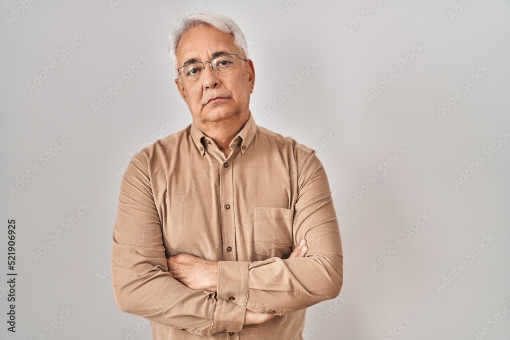 Hispanic senior man wearing glasses skeptic and nervous, disapproving expression on face with crossed arms. negative person.