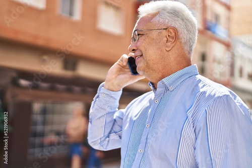 Senior man smiling confident talking on the smartphone at street