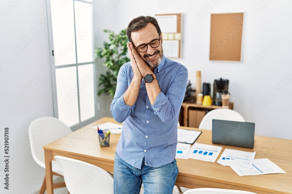Middle age hispanic man with beard wearing business clothes at the office sleeping tired dreaming and posing with hands together while smiling with closed eyes. Middle age hispanic man with beard wearing business clothes at the office sleeping tired dreaming and posing with hands together while smiling with closed eyes.