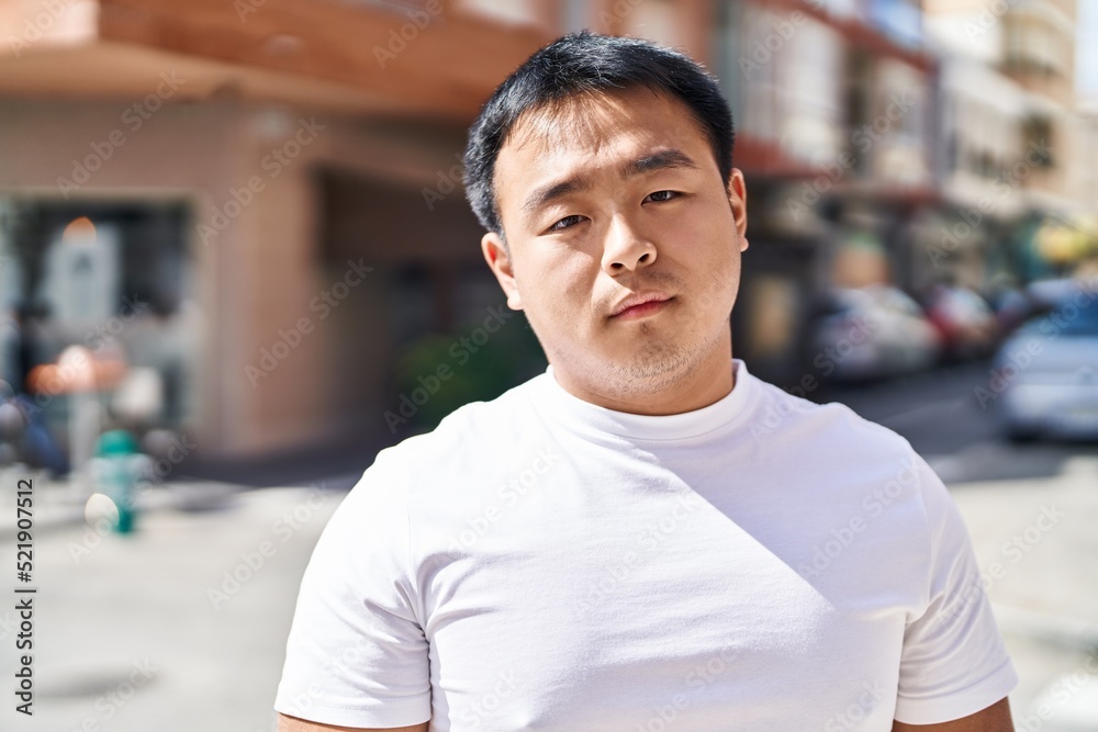 Young chinese man standing with relaxed expression at street Young chinese man standing with relaxed expression at street