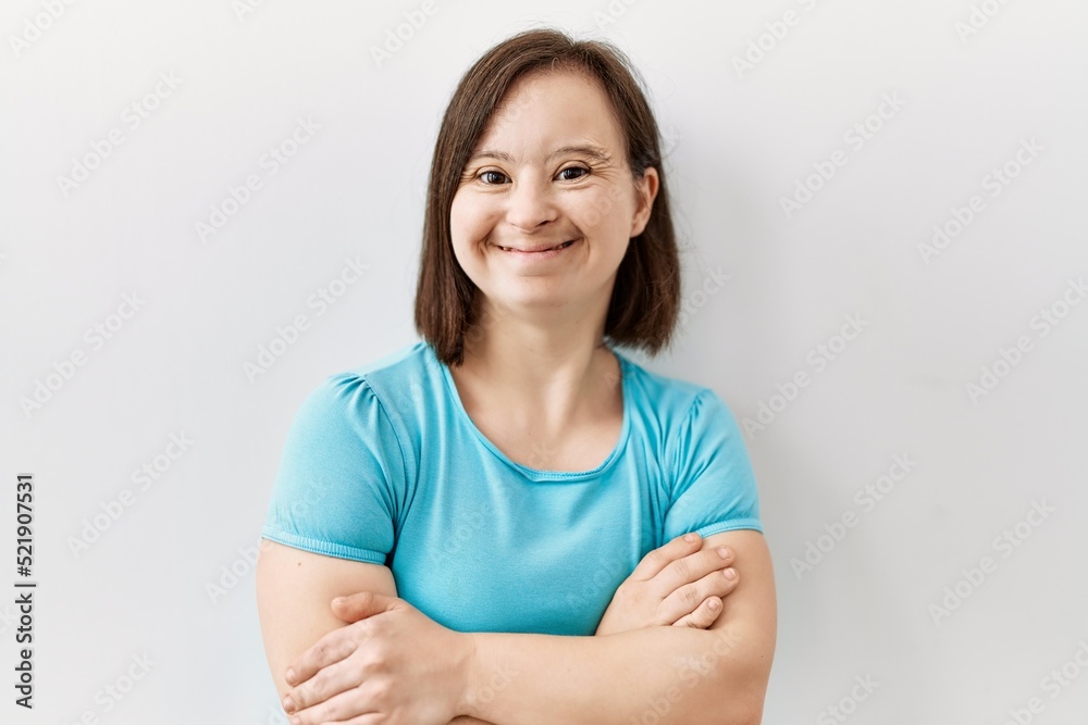 Young down syndrome woman standing over isolated background happy face smiling with crossed arms looking at the camera. positive person. Young down syndrome woman standing over isolated background happy face smiling with crossed arms looking at the camera. positive person.