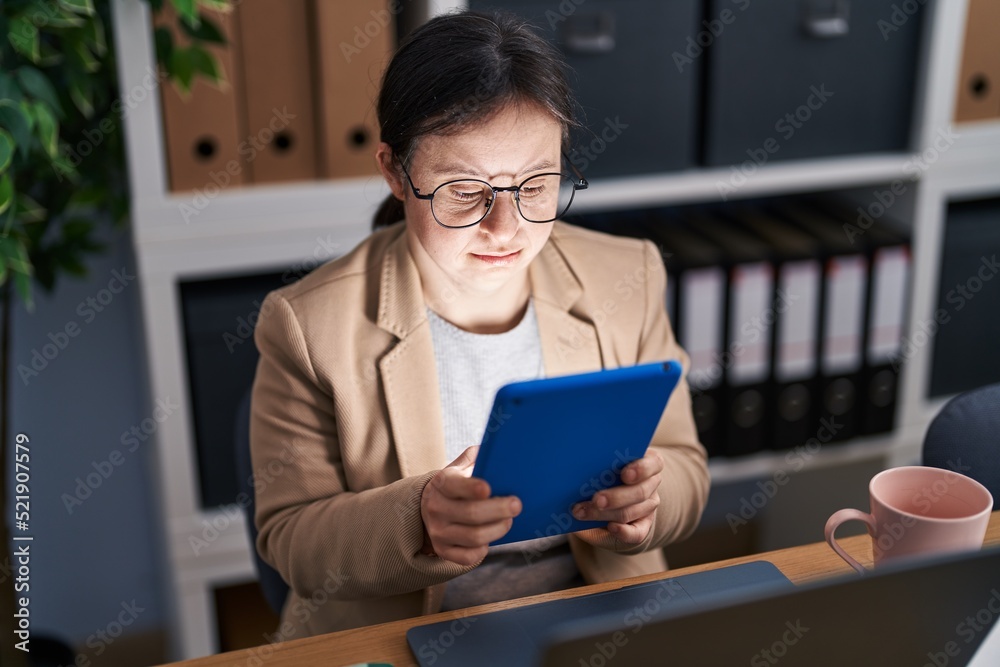 Young woman with down syndrome business worker using touchpad working at office Young woman with down syndrome business worker using touchpad working at office