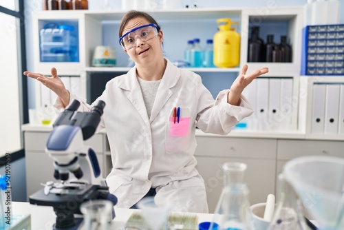 Hispanic girl with down syndrome working at scientist laboratory smiling cheerful offering hands giving assistance and acceptance.