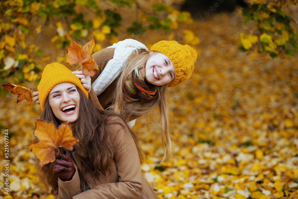 mom and child having fun time outside in city park in autumn