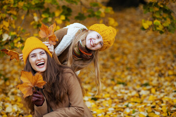 mom and child having fun time outside in city park in autumn