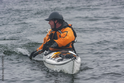 Kayak surfer on rough sea  by misty day on Nova Scotia coastlines, Canada