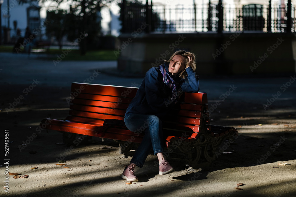 A woman sits sadly on a park bench.