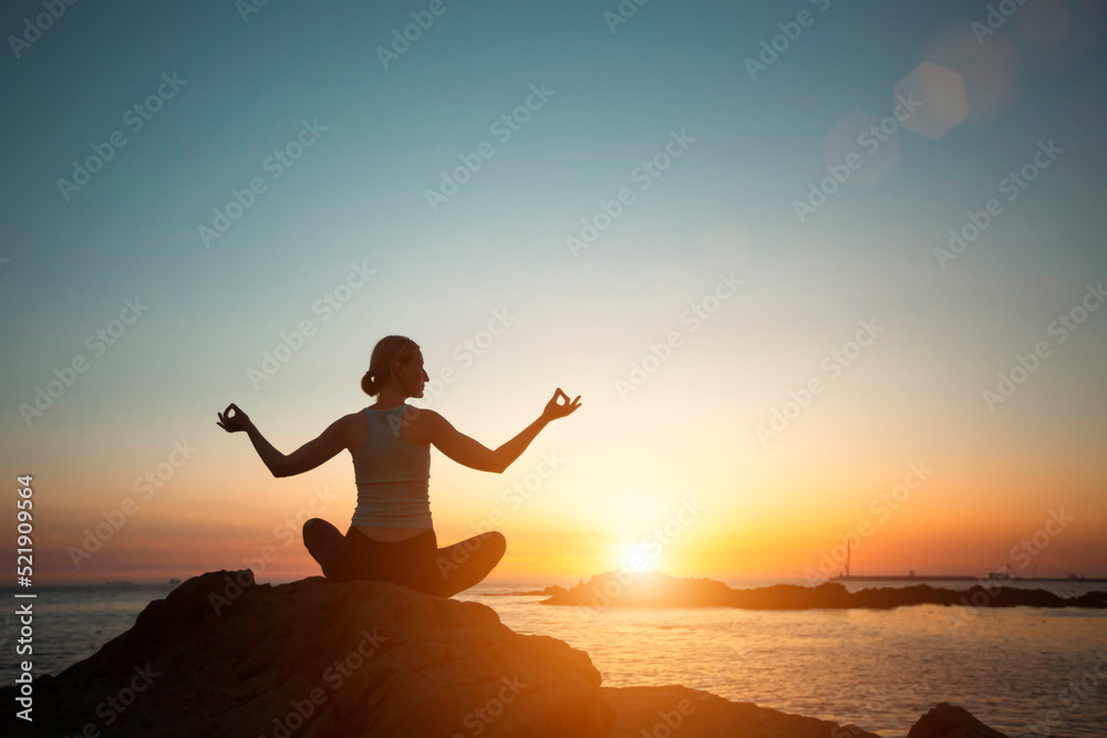 Yoga woman meditating in the sea beach during a beautiful sunset.  .