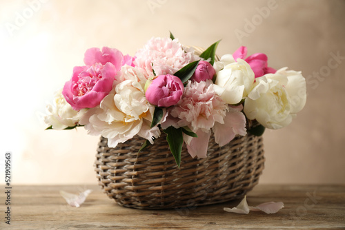 Beautiful peony bouquet in wicker basket on wooden table © New Africa