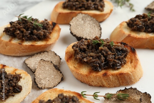 Delicious bruschettas with truffle sauce and thyme on white table, closeup