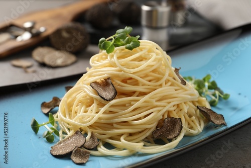 Delicious pasta with truffle slices and microgreens served on light grey table, closeup