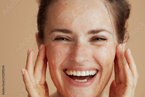 happy modern woman with face scrub against beige background photo