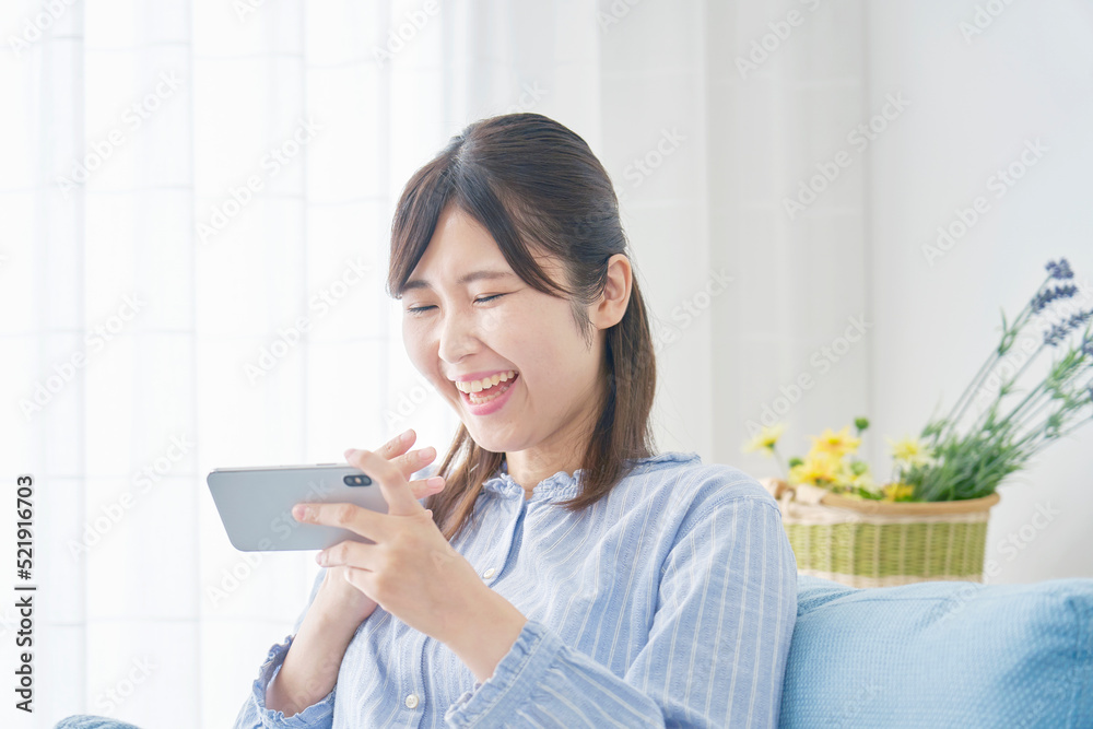 自宅でスマホで動画を見る笑顔の女性