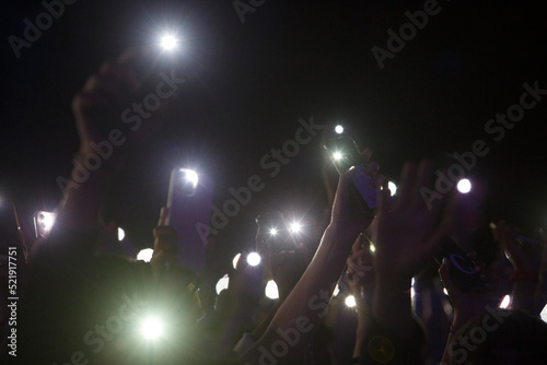 People holding smart phone with flash on and hands up