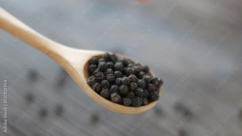 Whole black peppercorn in a wooden spoon on wooden background. Whole black peppercorn in a wooden spoon on wooden background.
