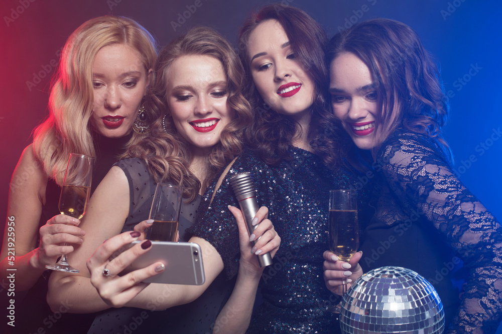 Group of partying women clinking flutes with sparkling wine and make selfie.