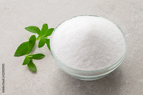 natural sugar substitute sweetener in a glass bowl with fresh stevia leaves. photo