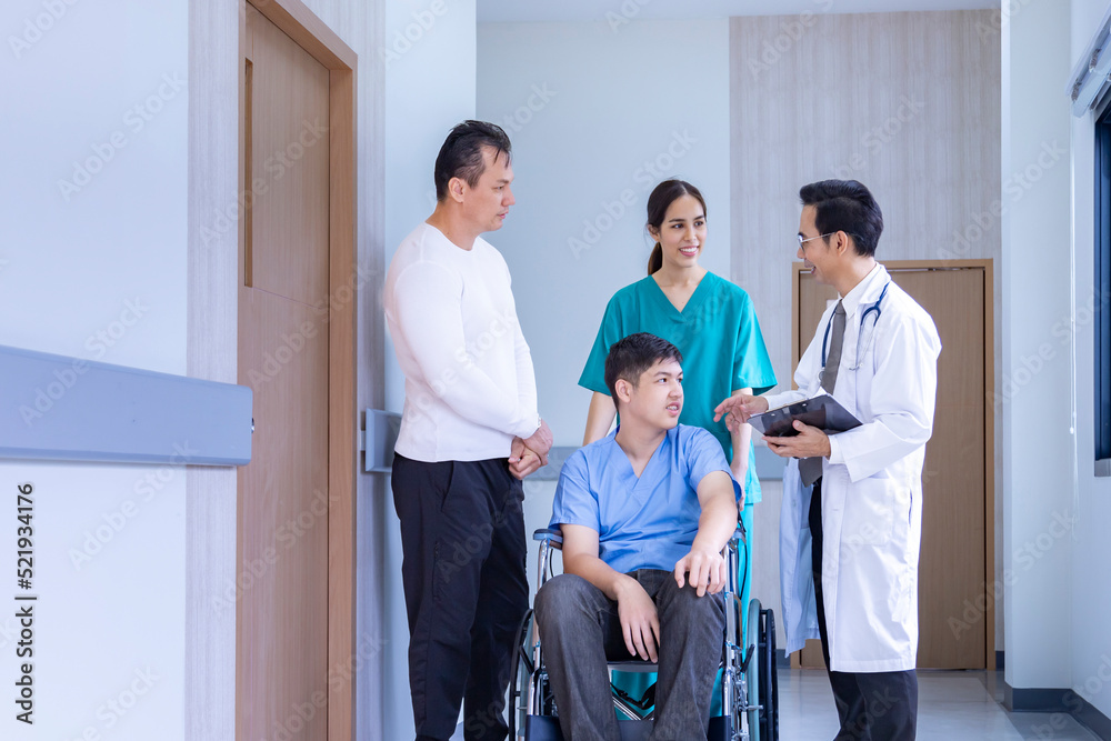 Team of doctor from is discussing with the nurse and parent about kid patient in wheelchair at his appointment in hospital for physical therapy after knee surgery from accident