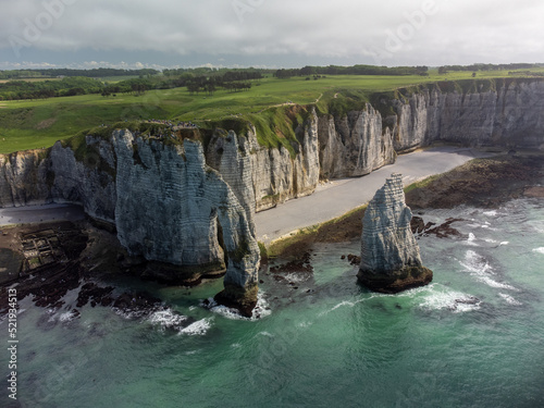 Low tide period and aerial view on ocean bed and chalk cliffs of Porte d'Aval arch in Etretat, Normandy, France. Tourists destination.