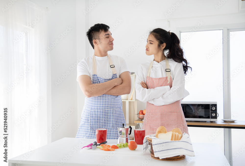 Asian couple playing while cooking together in the kitchen Asian couple playing while cooking together in the kitchen
