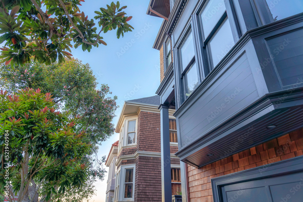 Close up of a house exterior with dark gray bay windows and wooden shingle sidings