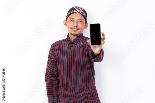 asian man with javanese traditional cloth lurik demonstrating mobile cell phone isolated on white background photo