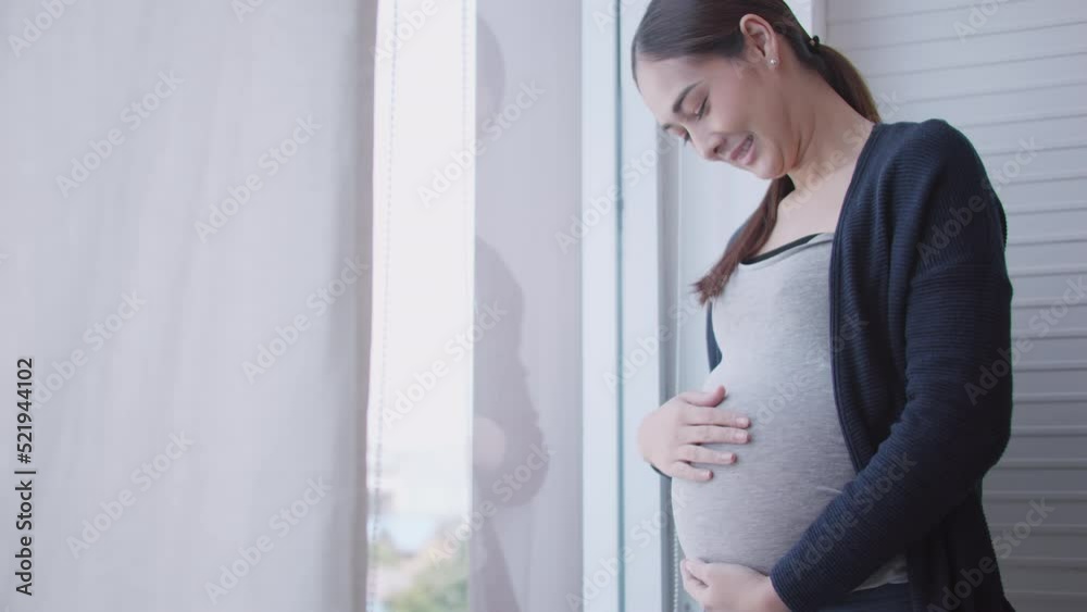 беременная женщина счастлива смотрит в окно