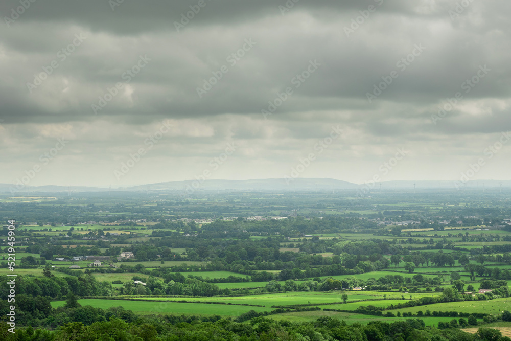 View on green Irish country side in county Tipperary. Agriculture land with pasture and small forests. Blue cloudy sky. Nature landscape.
