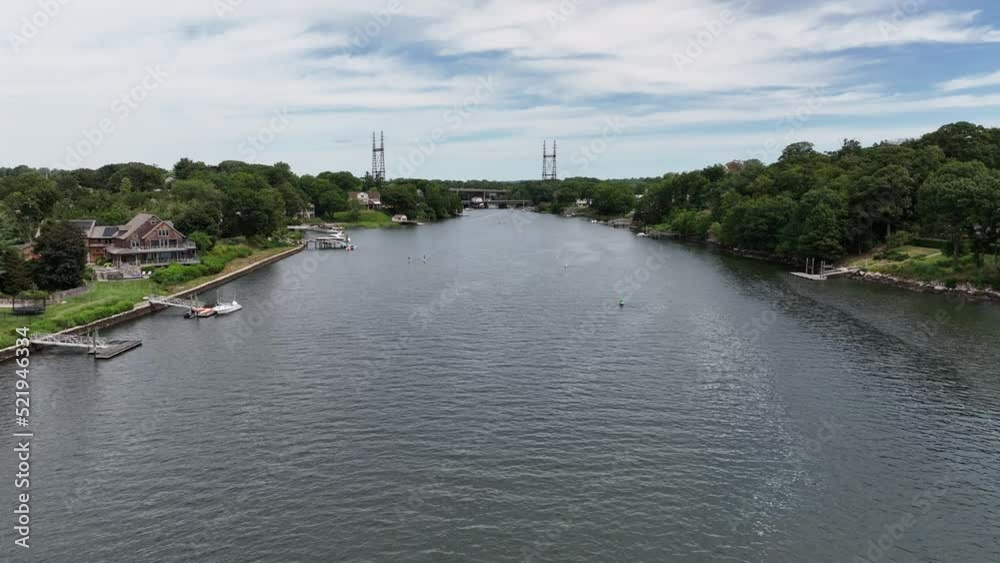 An aerial view over the Saugatuck River in Connecticut on a beautiful day with blue skies and white clouds. The camera dolly in towards a railroad bridge with two transmission towers in the distance. An aerial view over the Saugatuck River in Connecticut on a beautiful day with blue skies and white clouds. The camera dolly in towards a railroad bridge with two transmission towers in the distance.