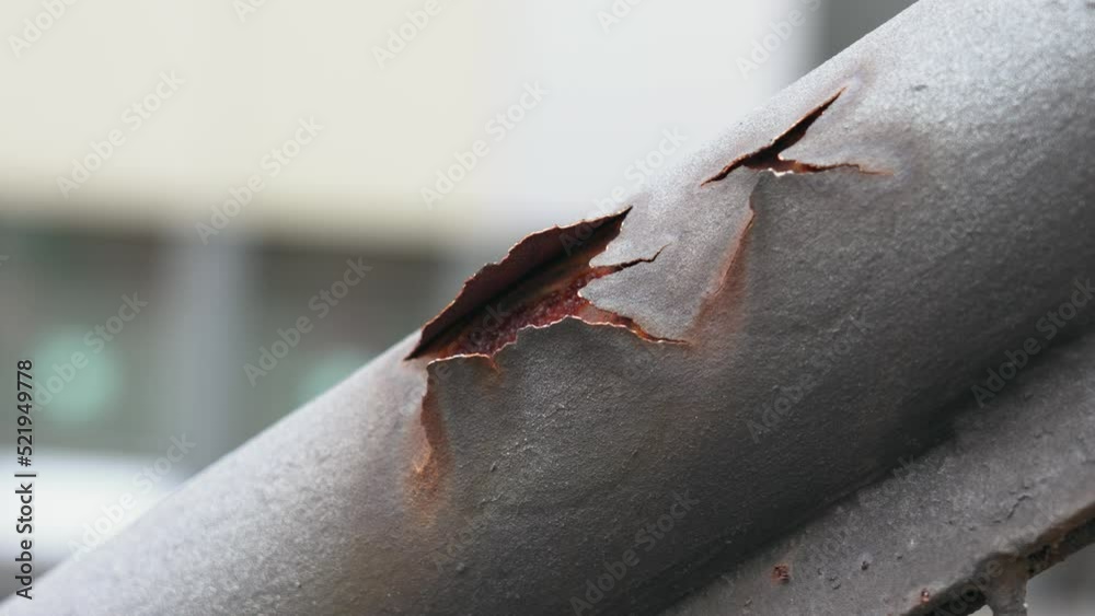 Peeled rust of corroded iron staircase handrail with cracked metal surface close up