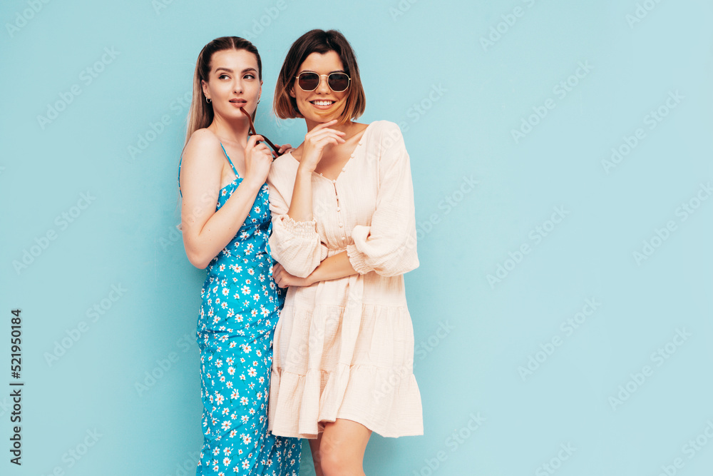 Two young beautiful smiling brunette hipster female in trendy summer shorts clothes. Sexy carefree women posing near blue wall. Positive models having fun. Cheerful and happy. Hugging Two young beautiful smiling brunette hipster female in trendy summer shorts clothes. Sexy carefree women posing near blue wall. Positive models having fun. Cheerful and happy. Hugging