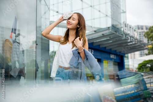 Angry female having sunstroke skin damage from sun UV city air pollution outside on street, Overheating Asian beautiful business woman drying sweat her face with cloth in warm summer day hot weather