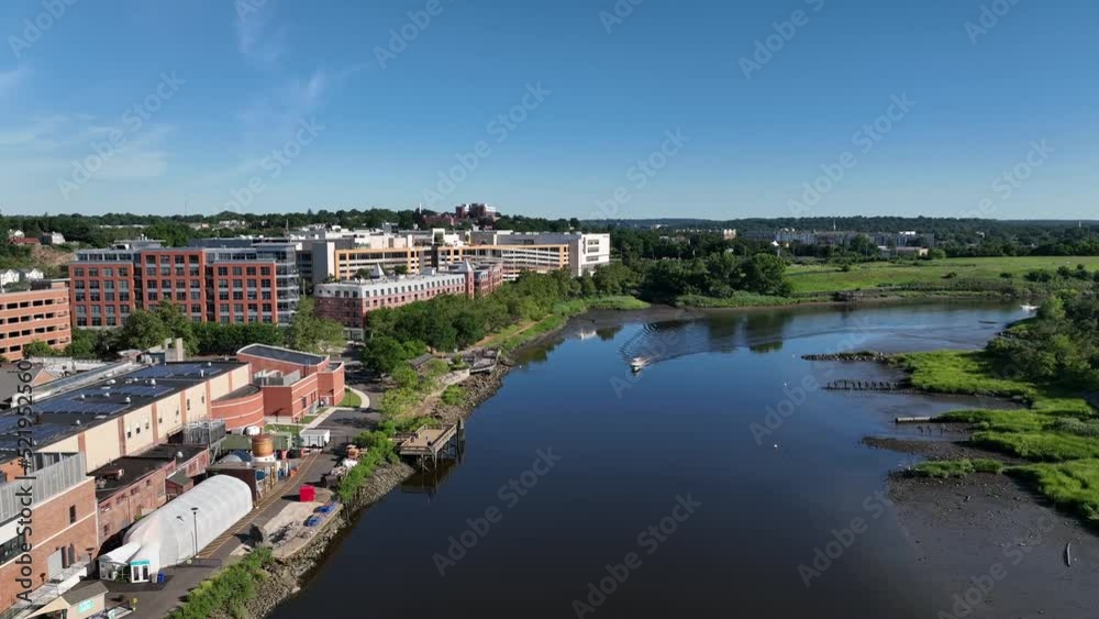 An aerial view over the Norwalk River on a sunny day. The drone camera dolly in and tilt down over the water as two small boats cruise towards the drone, creating ripples in the still river. An aerial view over the Norwalk River on a sunny day. The drone camera dolly in and tilt down over the water as two small boats cruise towards the drone, creating ripples in the still river.