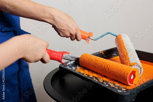 Canvas Print Woman and kid using roller brush and orange paint to renovate apartment room and change walls color