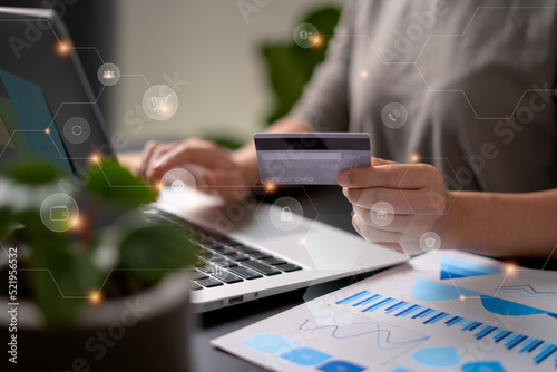 Close up shot of females hands holding credit card typing message on laptop for shopping online with technology icons.