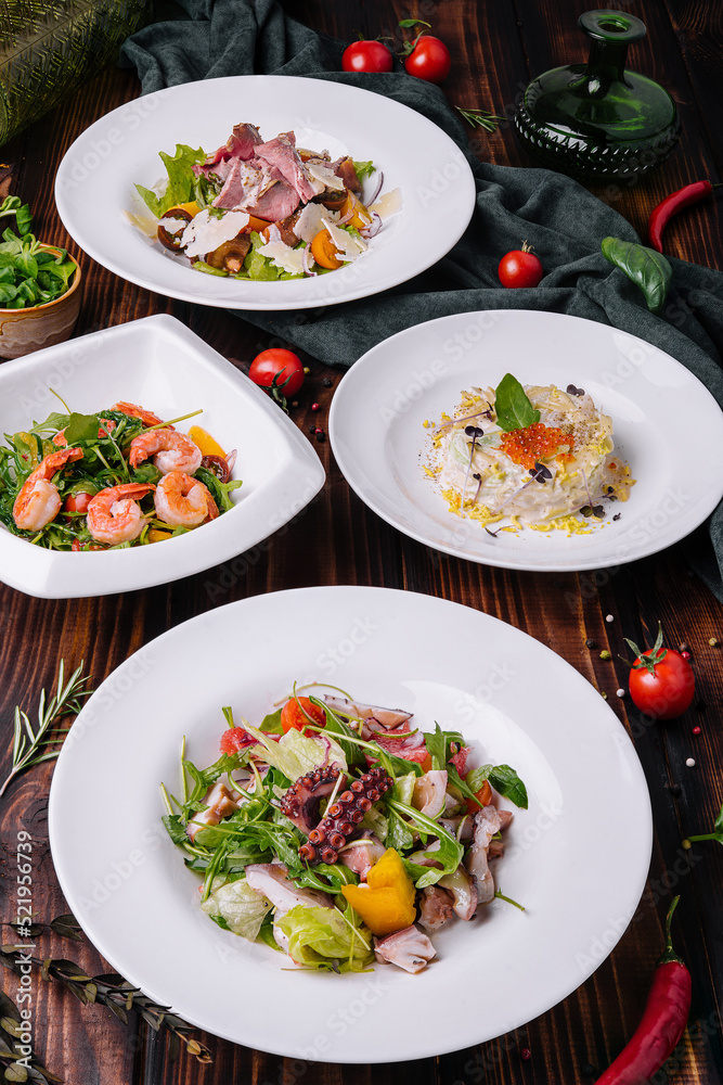 different salads in white plates on a wooden table different salads in white plates on a wooden table
