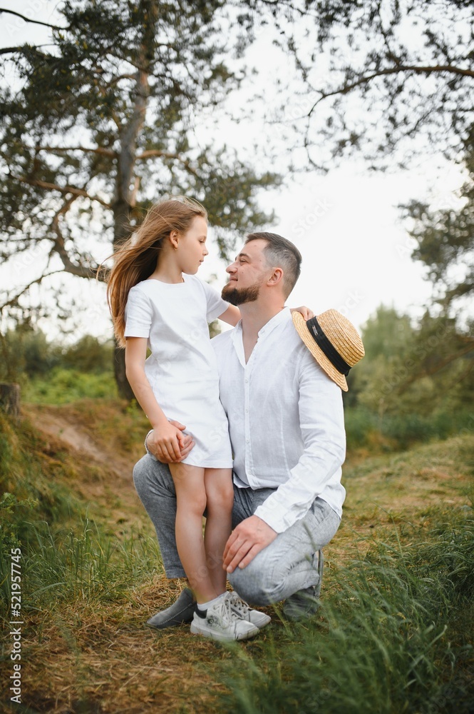 Fototapeta premium happy father and daughter playing while walking in a beautiful summer park. Ideal weekend father with his little daughter.
