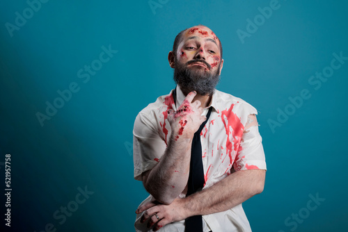 Dangerous cruel zombie brainstorming ideas, acting pensive and thoughtful while having bloody wounds. Aggressive evil monster thinking about eating brain, doomsday apocalypse in studio.