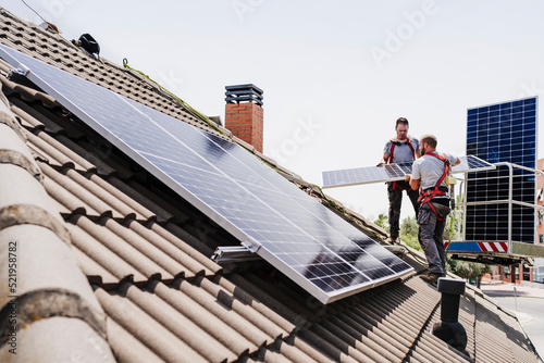 Electricians installing solar panels on rooftop photo
