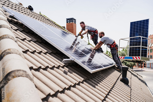 Craftsmen installing solar panels on rooftop of house photo
