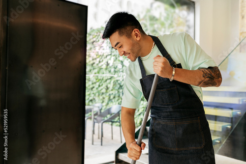Smiling man with broom cleaning in coffee shop photo