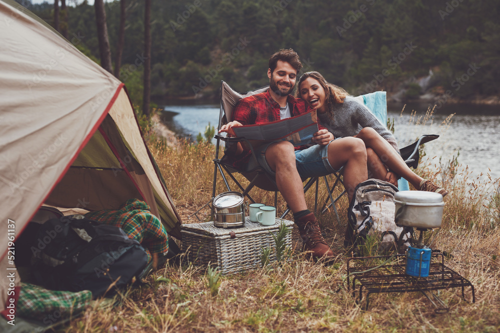 Loving couple reading a travel map while camping by the lake - obrazy, fototapety, plakaty 