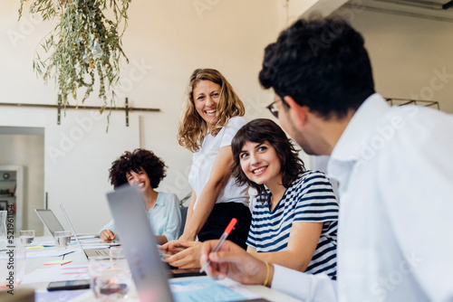 Happy businesswomen looking at colleague in office